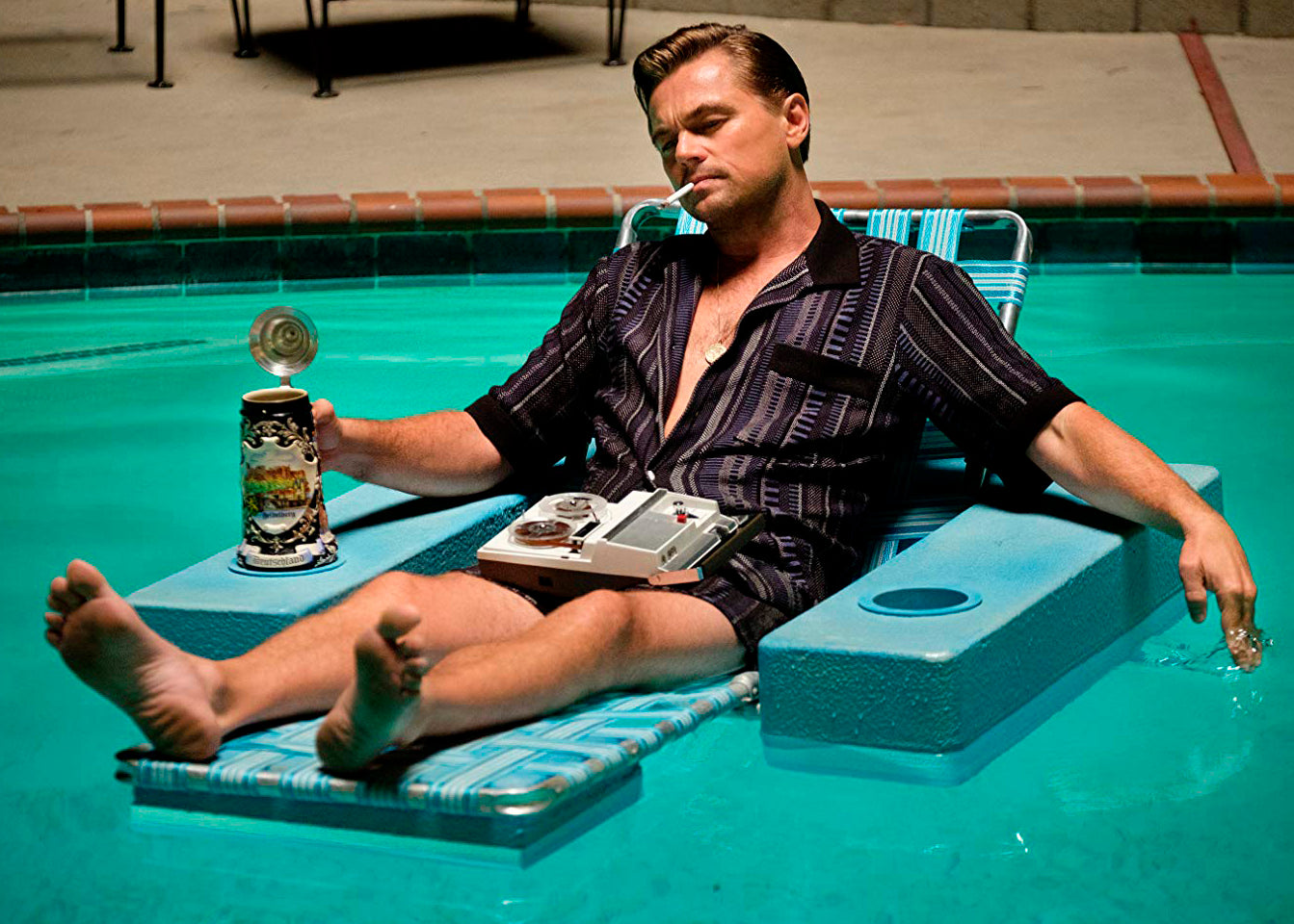 Flatlay of Sand2Sea luxury floating beach bag surrounded by vintage film props and retro poolside accessories