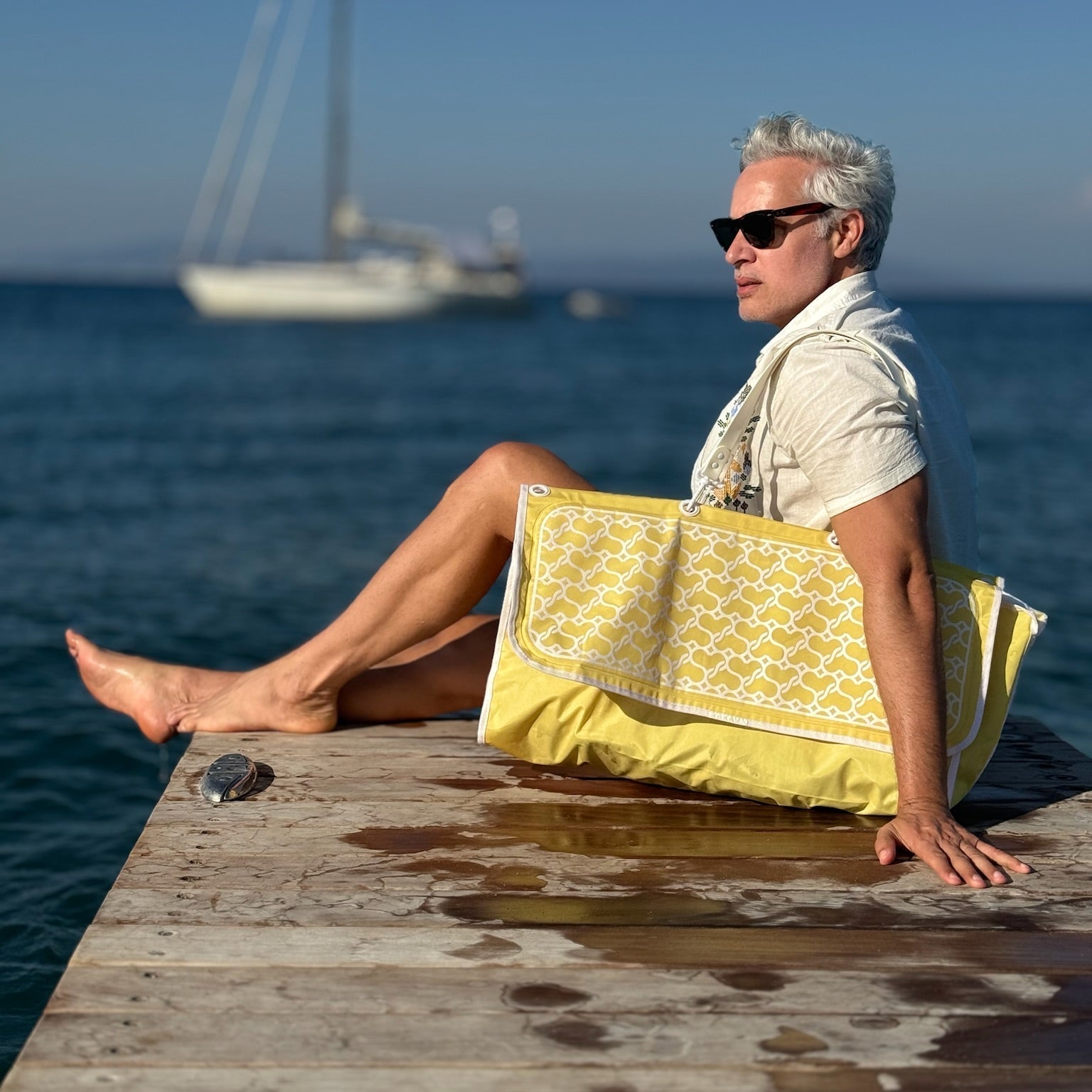 Man floating near a Mykonos beach using a Sand2Sea inflatable beach bag with a luxury float design